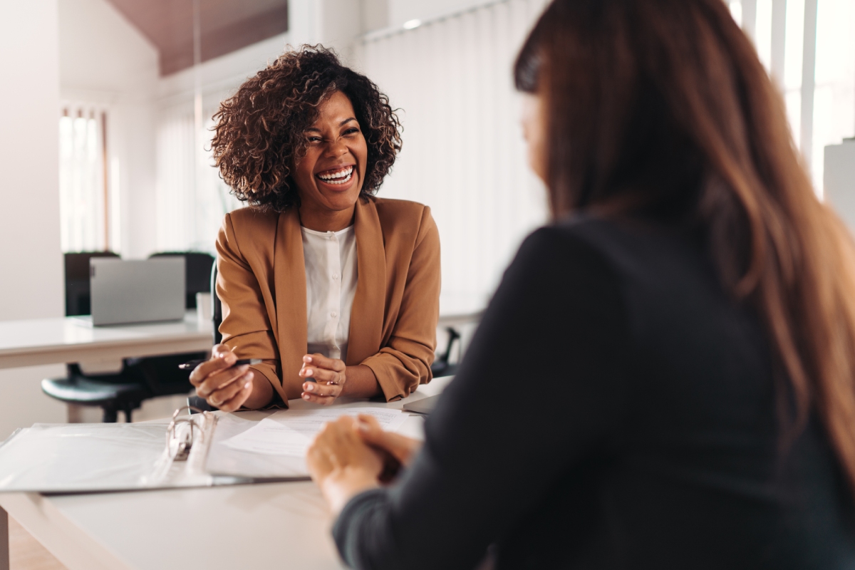 Échange professionnel chaleureux entre deux femmes lors d'un rendez-vous en bureau