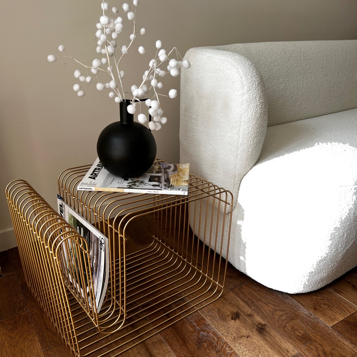 Salon minimaliste, canapé blanc bouclé et table d'appoint dorée avec vase décoratif